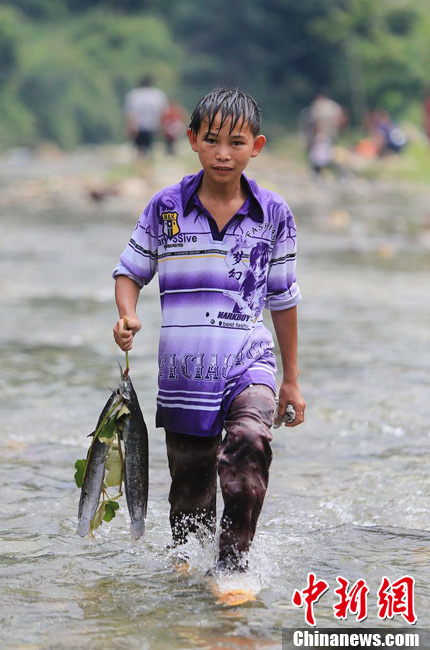 圖為7月9日，一名男孩在鬧魚節(jié)活動(dòng)中抓到了兩條魚。譚凱興 攝