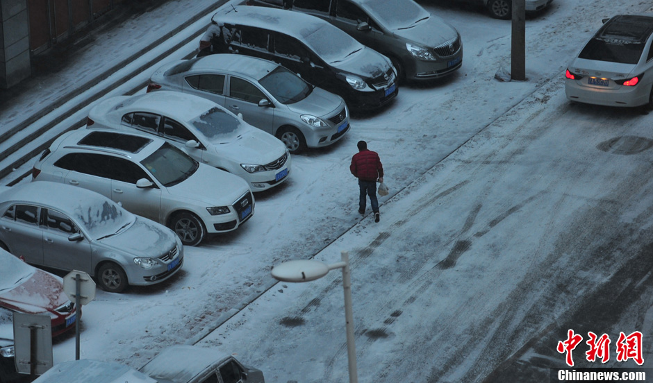 11月18日，行人在沈陽(yáng)街頭的積雪中穿行。