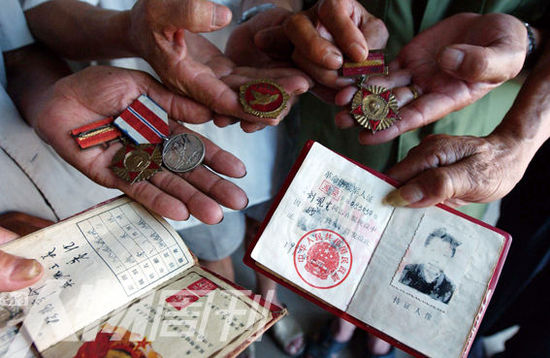 幾位志愿軍老兵展示自己的立功證、傷殘軍人證與勛章