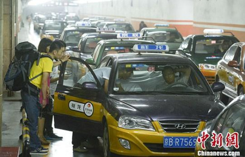 市民在北京西客站出租車候車點(diǎn)準(zhǔn)備乘車。中新社發(fā) 侯宇 攝
