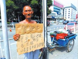 老人舉著牌子在路邊等候失主。京華時報記者譚青攝