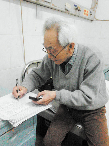 杜修源老人埋頭寫著特殊的“日記”。 李卓 攝