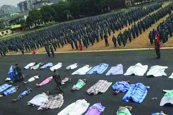 20多名女生躺在瀝青跑道上，身上嚴嚴實實地裹著棉被，接受太陽的照曬。