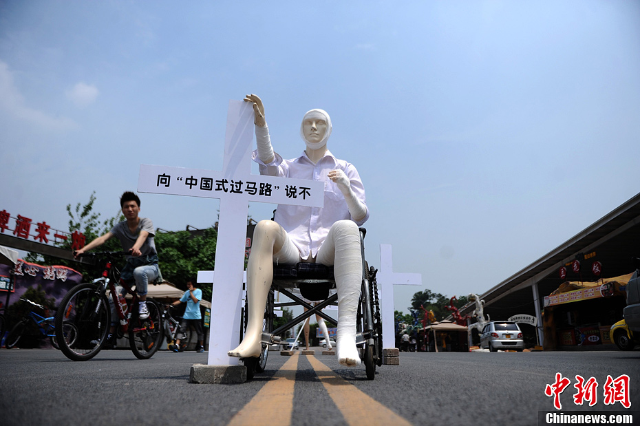 4月16日，重慶市洋人街上擺放著兩個(gè)受了傷的塑料人像“模特”，旁邊十字架上寫著向“中國式過馬路”說不