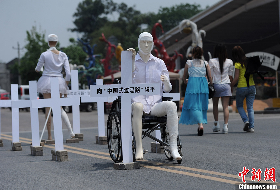4月16日，重慶市洋人街上擺放著兩個(gè)受了傷的塑料人像“模特”，旁邊十字架上寫著向“中國式過馬路”說不