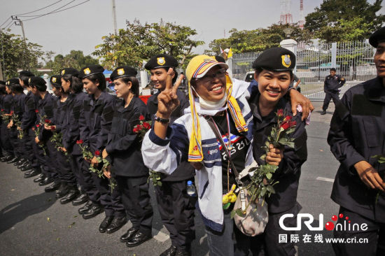 2013年12月03日,曼谷總理府與曼谷警署允許反政府示威民眾進入,雙方進入暫時“停戰(zhàn)”狀態(tài)迎接泰王生日。曼谷警察總署,女警們手持鮮花送給反政府示威民眾。圖片來源:Manish Swarup/東方IC
