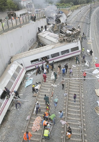 24日，救援人員在西班牙列車脫軌現(xiàn)場。一節(jié)車廂被強大的慣性拋上鐵道邊的高臺。