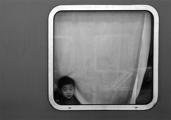 一個(gè)孩子把頭伸向窗外，他想再看送別的親人一眼