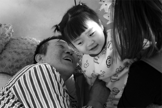 病床前李剛父女倆說(shuō)著“悄悄話”，幸福的氣氛洋溢在病房中