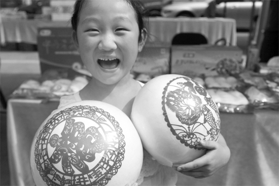在2013河南食品安全宣傳周活動(dòng)現(xiàn)場(chǎng)，一個(gè)小女孩抱著參展的特色大饅頭樂(lè)開(kāi)了花