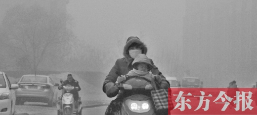 12月8日，鄭州市未來路上，一位市民帶著孩子在霧中騎行