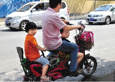 周先生騎著一輛低矮的電動(dòng)車(chē)帶著一對(duì)兒女，很不安全。