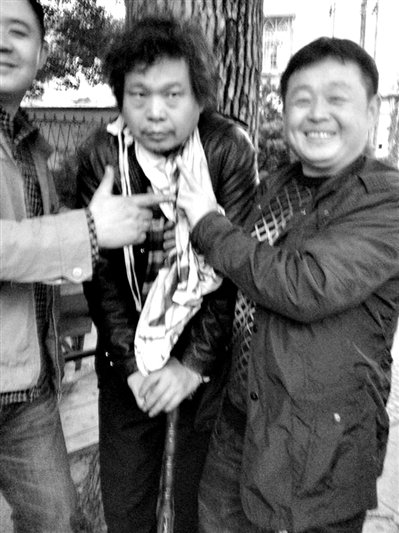 兩名接訪人員與患有癌癥的訪民段新德合影時，面帶笑容擺出勝利的手勢。