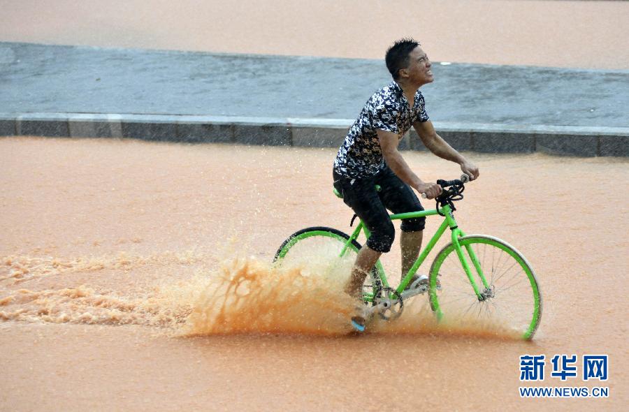 5月11日，一名行人在深圳街頭冒雨騎行。