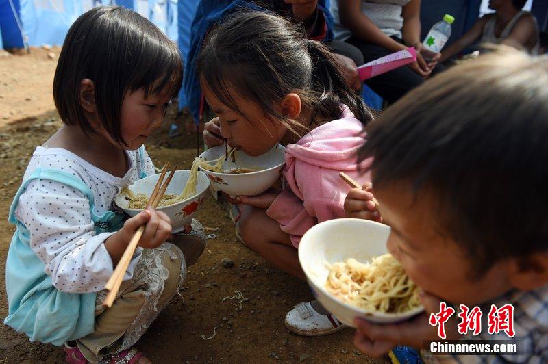 2014年8月6日，云南魯?shù)辇堫^山災(zāi)區(qū)，兒童在帳篷外吃飯。