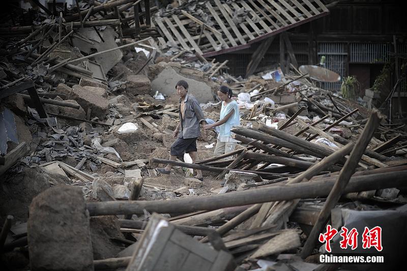 2014年8月5日，云南昭通龍頭山鎮(zhèn)老街，一對夫妻從居住房屋的廢墟中走過。