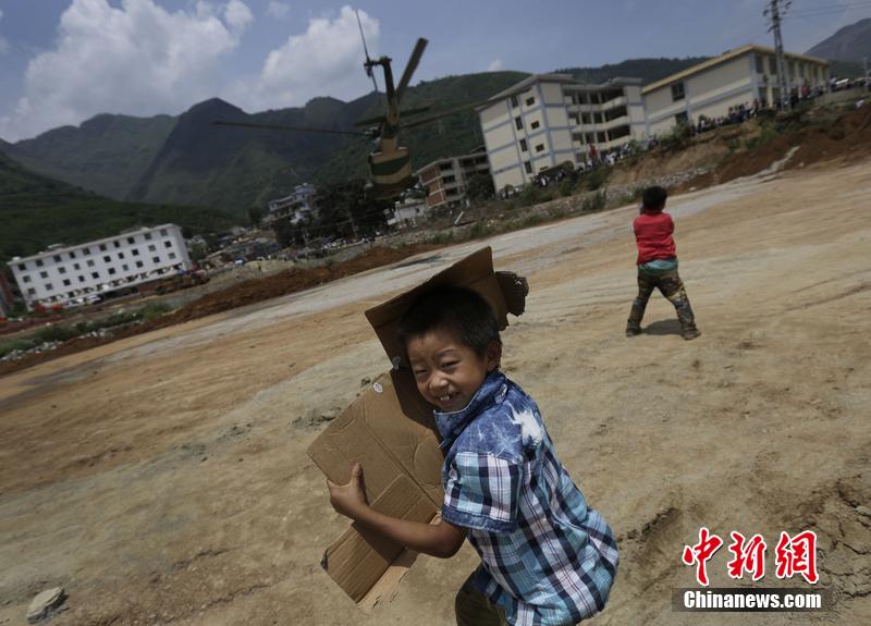云南省昭通市魯?shù)榭h發(fā)生6.5級地震。幾個孩子在直升機降落的平地上玩耍。