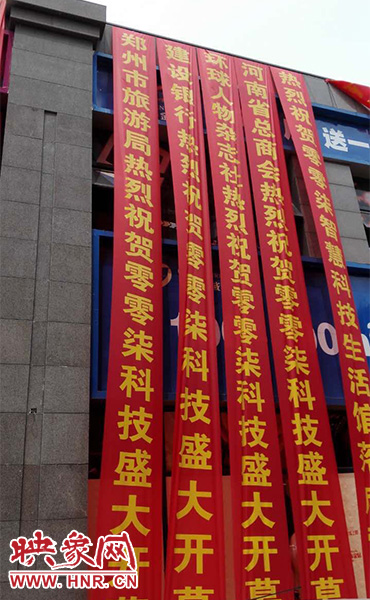 路邊一棟樓上懸掛著二三十條紅色條幅，全部是祝賀一家公司開(kāi)業(yè)的。