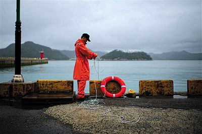 7月6日，韓國珍島，一名海岸警察在港口系救生圈。4月，客輪在珍島近海發(fā)生沉船事故后，仍有11人下落不明。